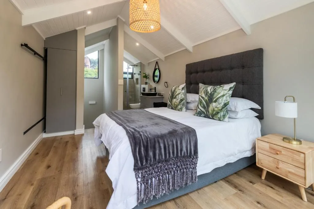 Bright bedroom with queen bed, dark headboard, and ensuite bathroom visible