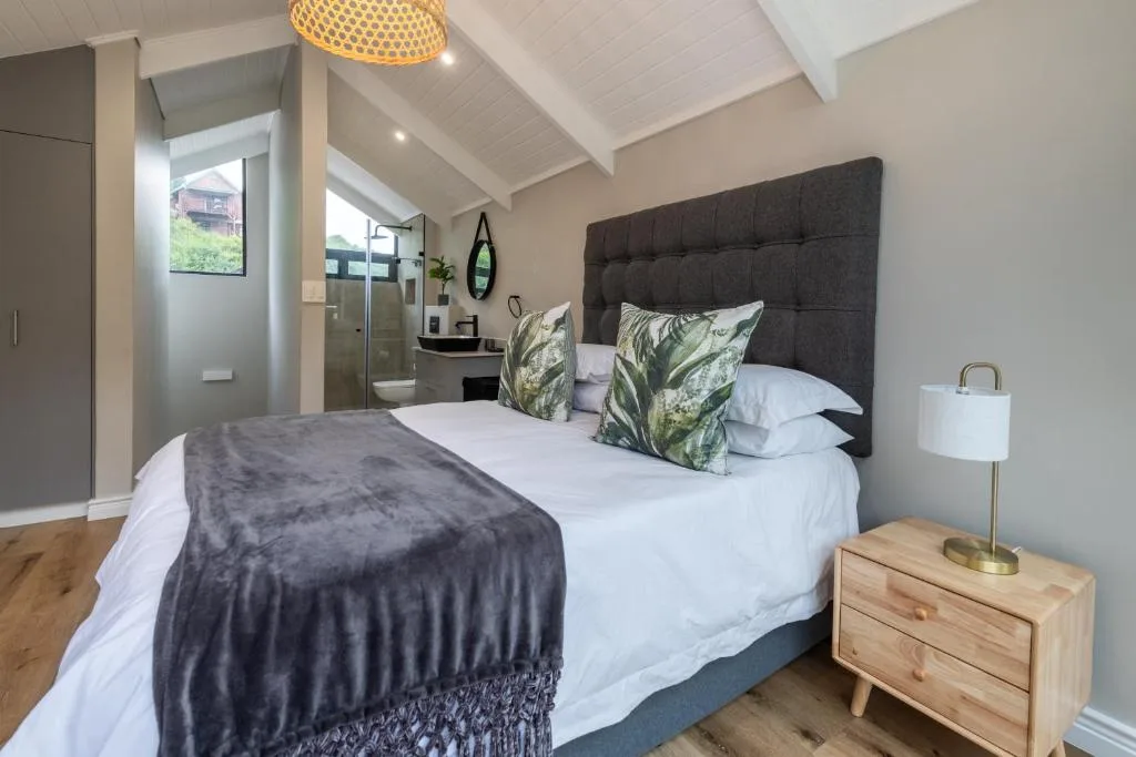 Modern bedroom with dark upholstered headboard and ensuite bathroom access