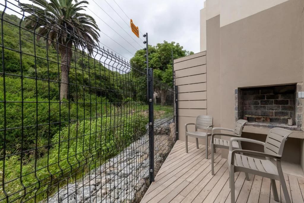 Outdoor deck with seating chairs and built-in braai overlooking green garden