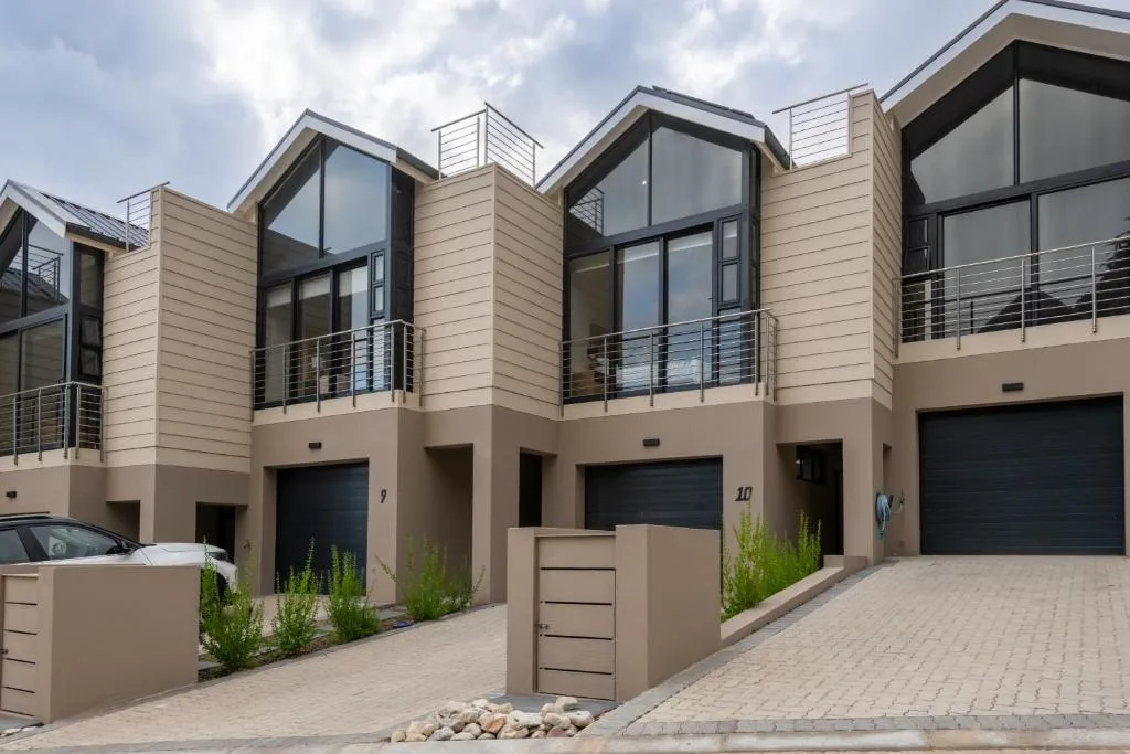 Modern beige townhouses with dark garage doors and metal railings