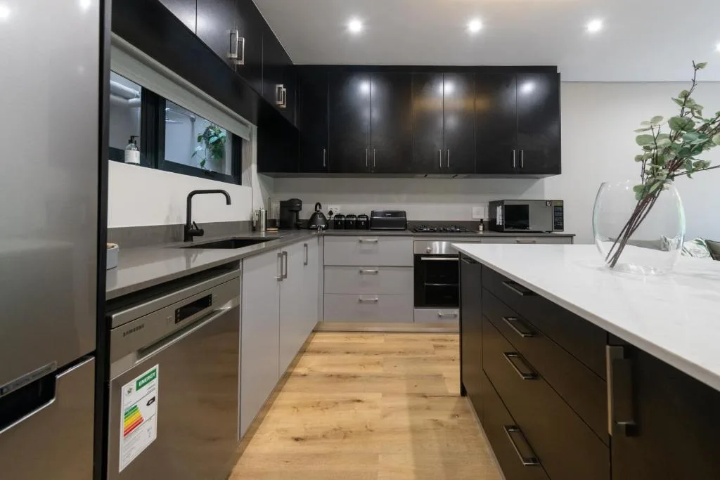 Modern kitchen with black cabinetry, stainless steel appliances, white countertops