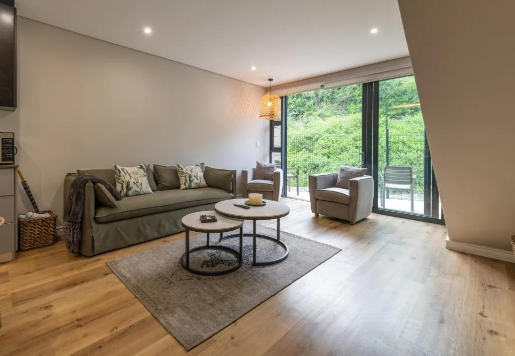 Modern lounge with grey sofa, armchair, and glass doors overlooking garden
