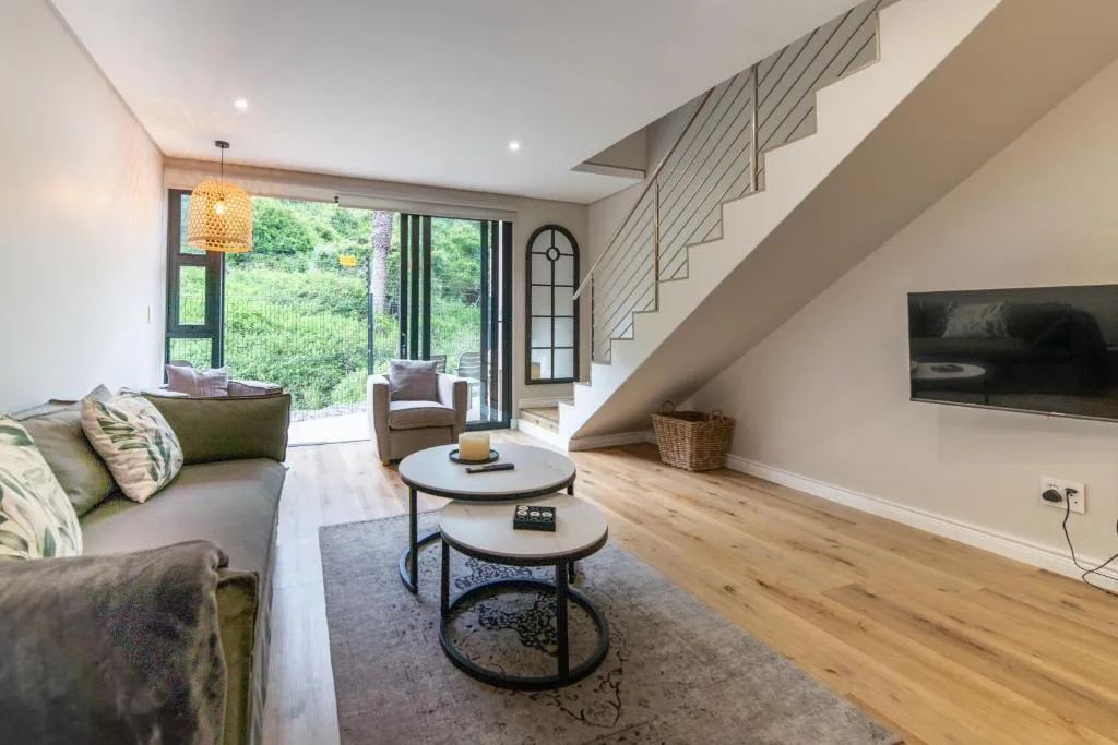 Modern living room with sofa, round coffee tables, TV, and garden views