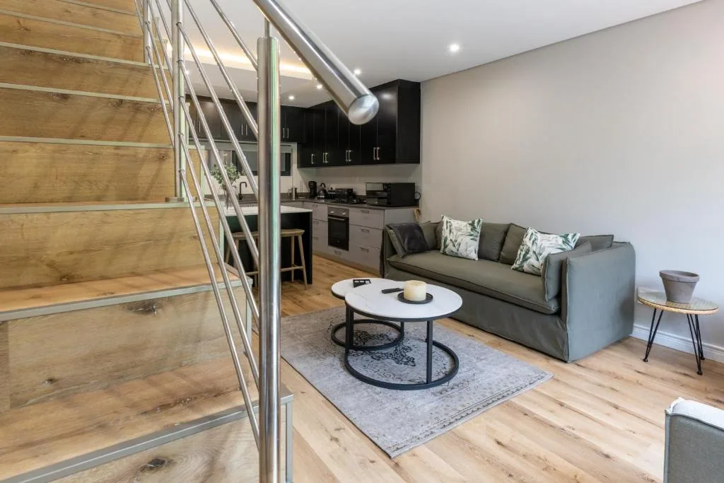 Open-plan lounge with gray sofa, coffee table, and modern staircase