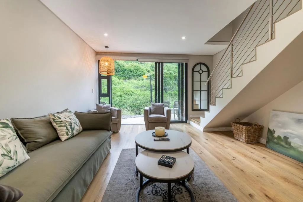 Modern living room with olive sofa, round coffee tables, and garden view doors