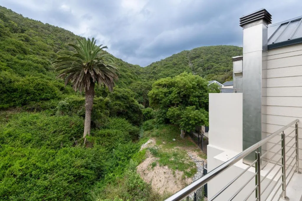 Lush green valley and forested hills from modern villa deck railing