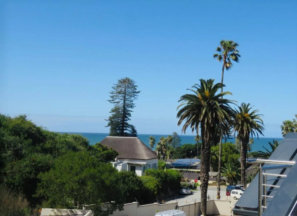 Ocean view across palm trees and coastal vegetation toward blue sea