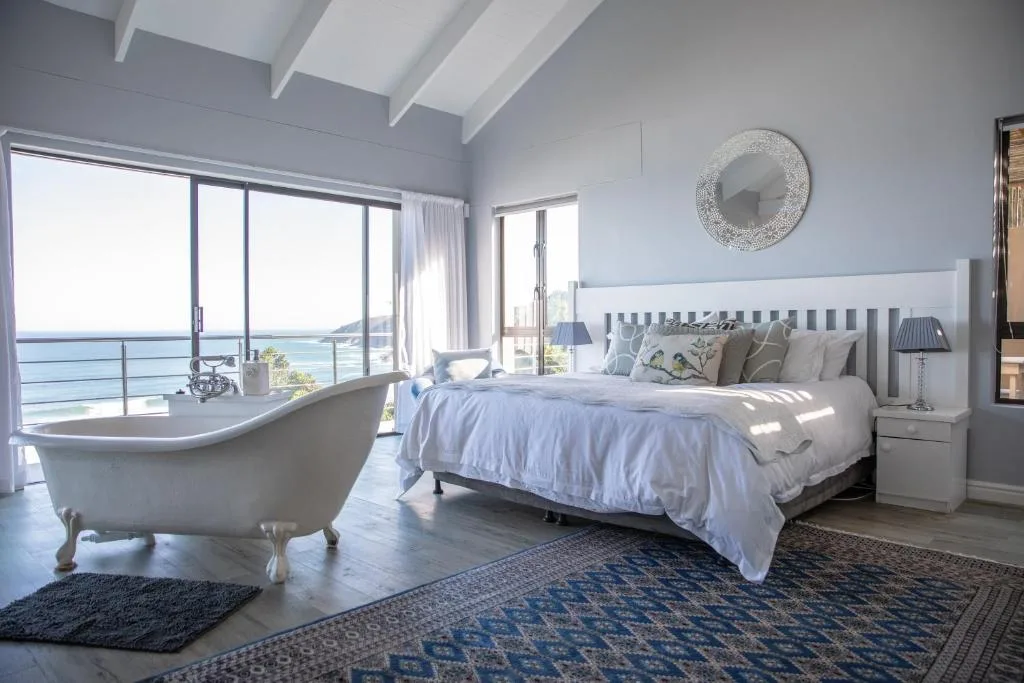 Luxury bedroom with ocean views, freestanding bathtub, and coastal decor