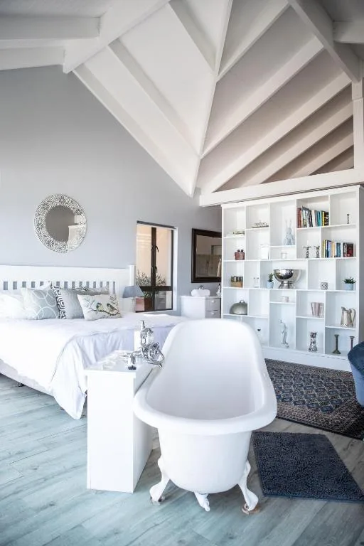 Bright loft bedroom with freestanding bath and exposed beam ceiling