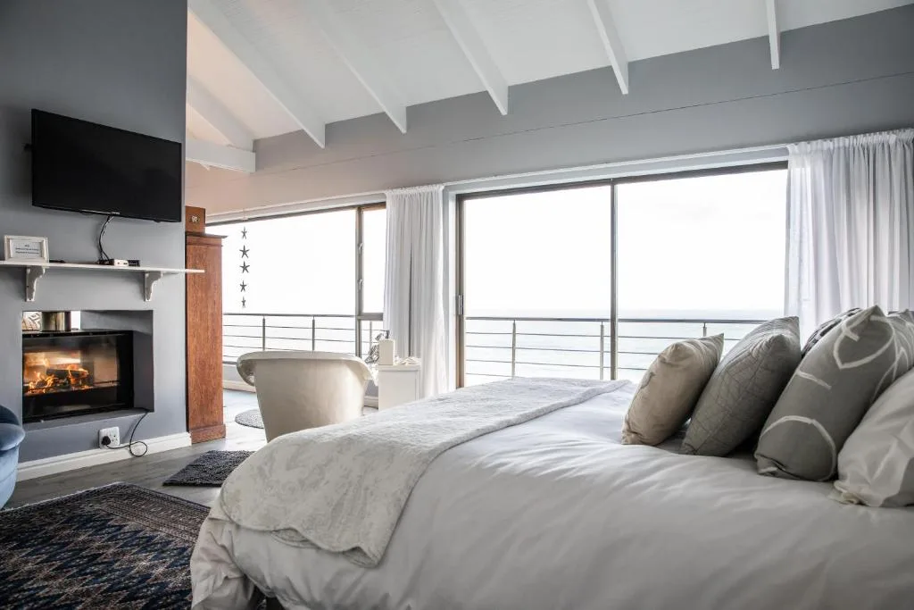 Modern bedroom with fireplace, ocean view, and contemporary furnishings