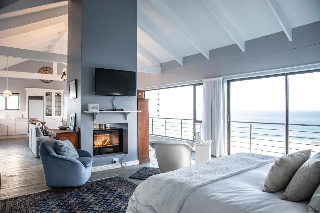 Spacious bedroom with ocean view and modern fireplace accent