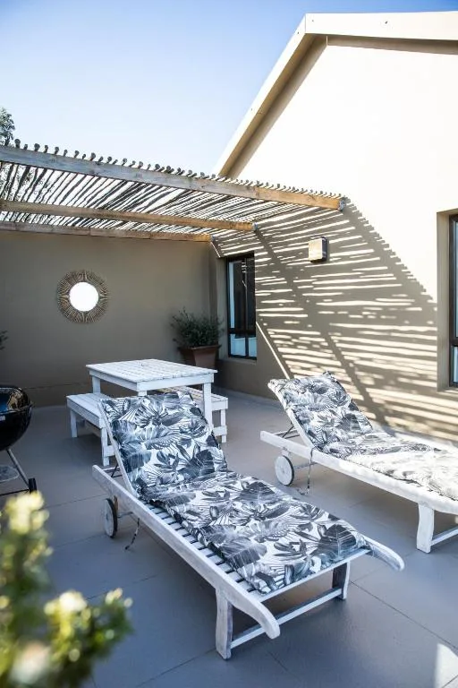 Modern patio with lounge chairs, dining table, and pergola shade structure