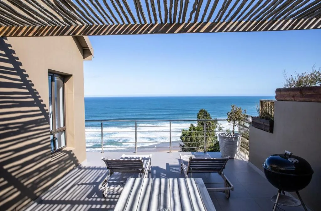Ocean-view deck with loungers, pergola shade, and braai grill