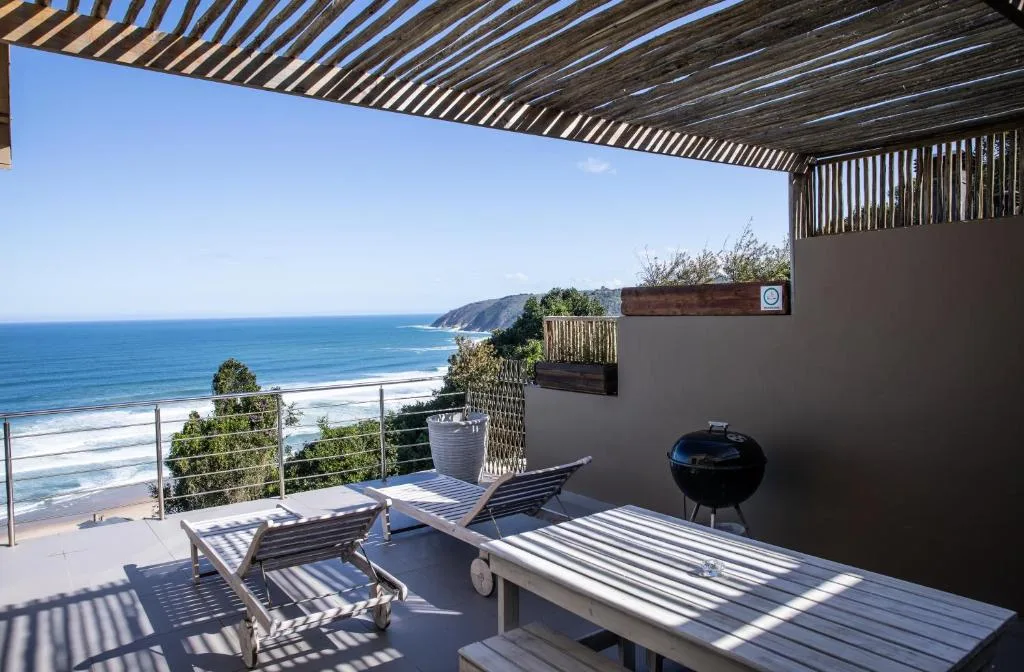 Oceanfront deck with lounge chairs, pergola shade, and coastal view