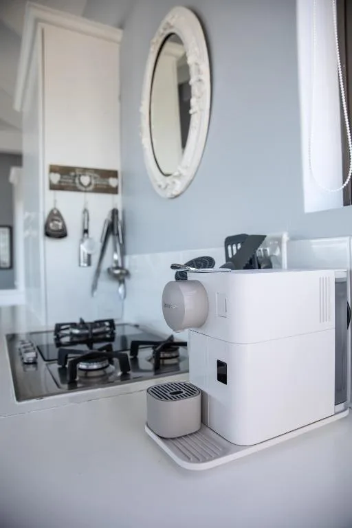 Modern white coffee machine and round mirror in contemporary bathroom vanity