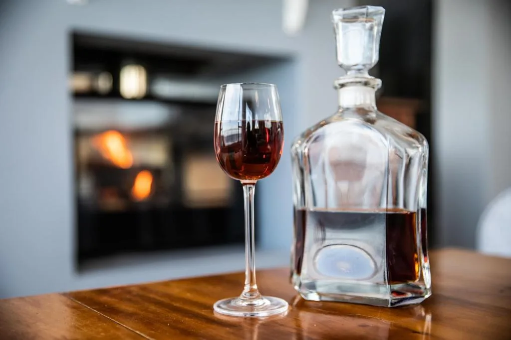 Wine glass and decanter with red wine on wooden table