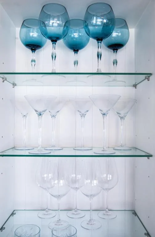 Glass shelving unit displaying blue and clear wine glasses and stemware