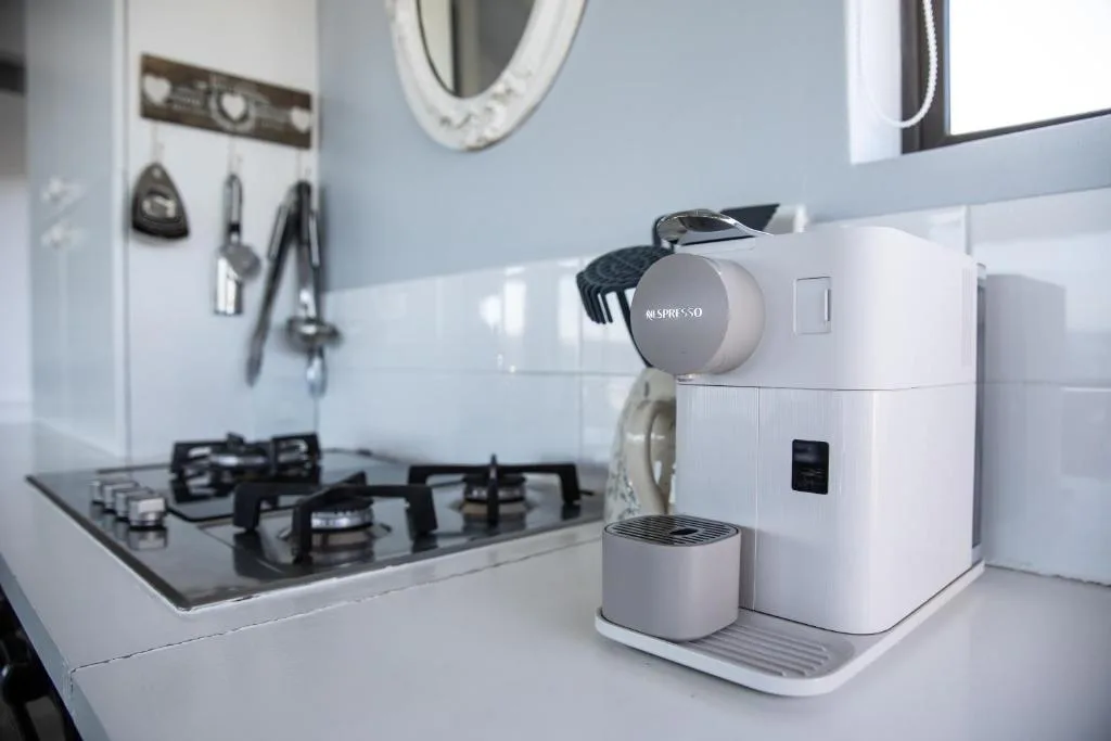 Modern kitchen with gas cooktop, coffee machine, and white appliances