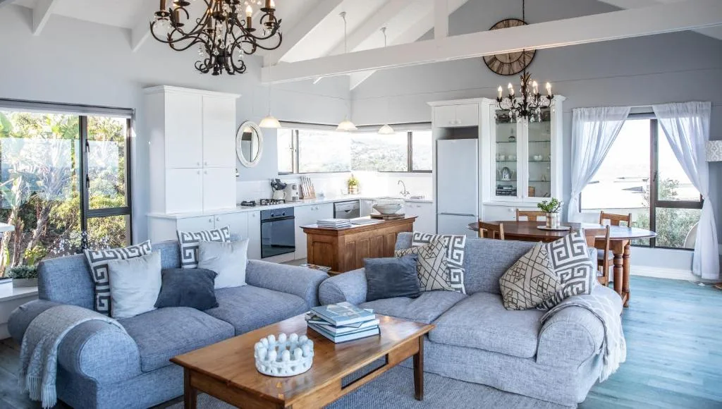 Open-plan lounge with blue upholstered sofa, wooden coffee table, and chandeliers overhead