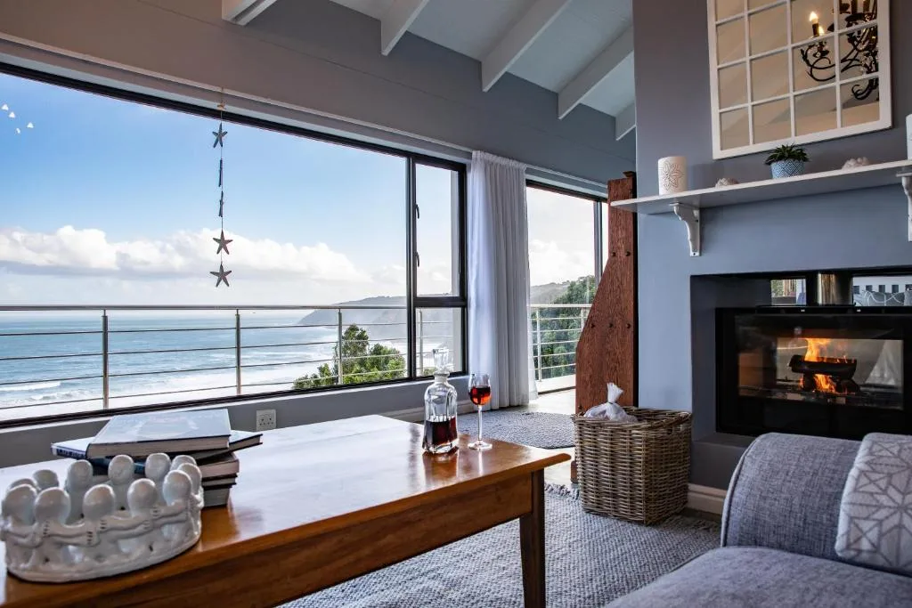 Modern lounge with fireplace, ocean views through large windows, and coastal decor