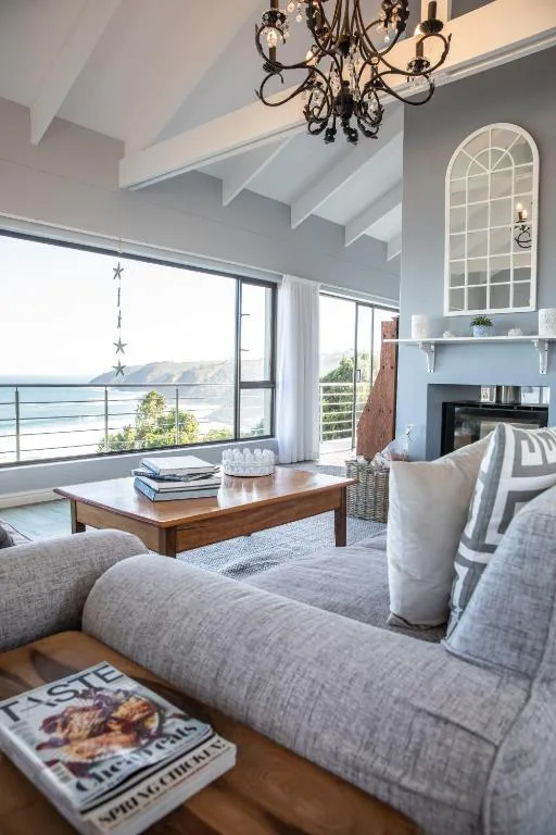 Bright modern lounge with gray upholstered sofa, wooden coffee table, and ocean views through large windows