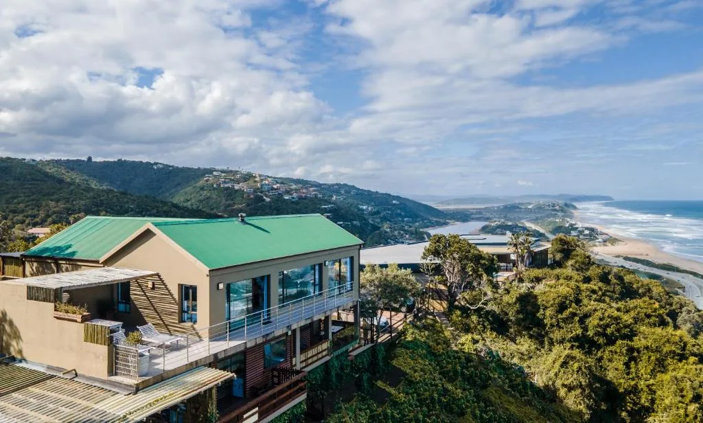 Elevated coastal vista showing beach, lagoon, and forested hillside landscape
