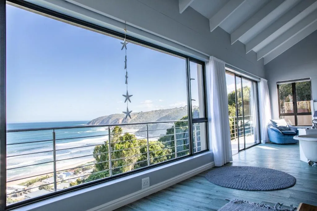 Panoramic ocean and coastline view through large windows with railing