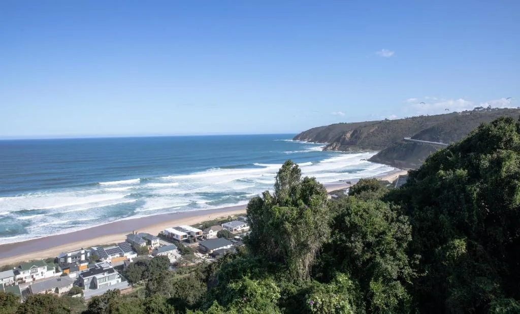 Coastal beach vista with golden sand, rolling waves, and dramatic cliffs