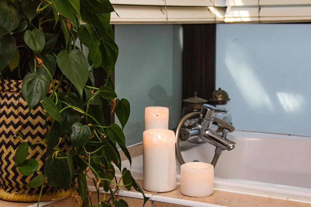 Bathroom vanity with candles, plants, and chrome faucet fixtures