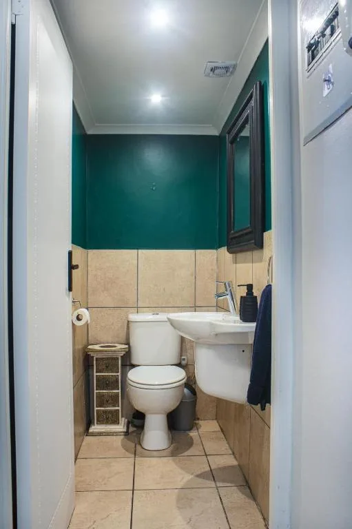 Modern bathroom with toilet, sink, and teal accent wall tiling