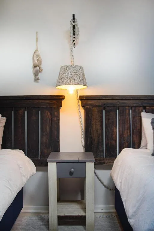 Twin beds with white linens and decorative rope pendant lighting