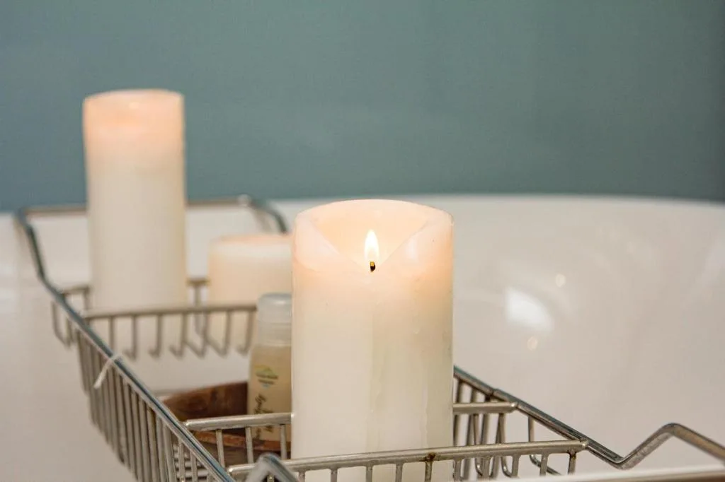 Lit candles in wire basket on bathroom edge, spa ambiance