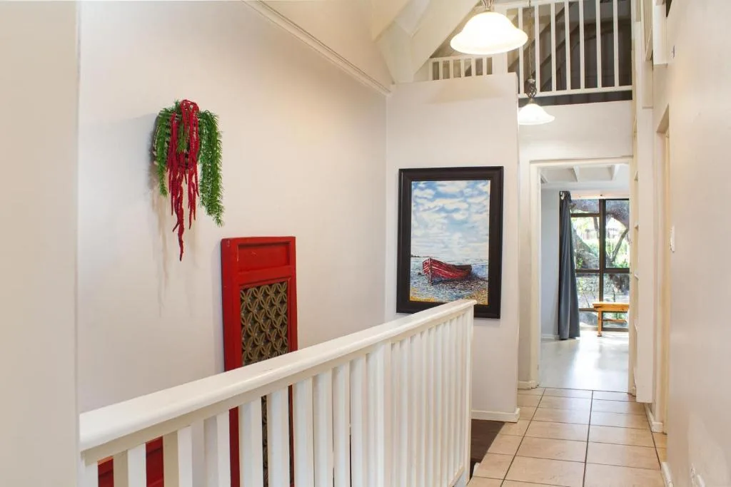Bright hallway with white railings, coastal artwork, and festive red decoration