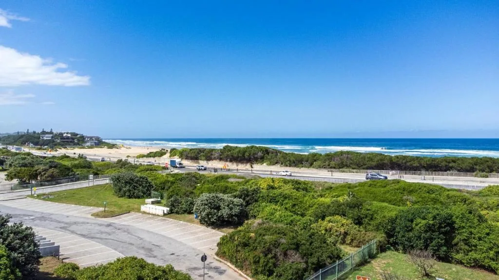 Sweeping coastal vista with pristine beach, ocean, and green vegetation
