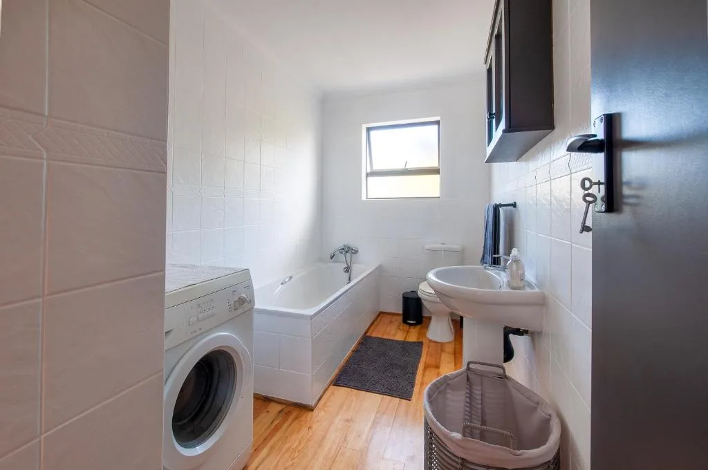 Modern bathroom with bathtub, sink, toilet, and washing machine