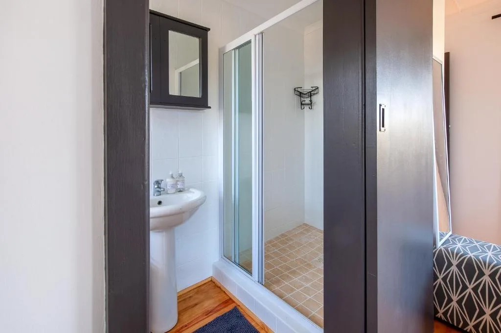 Modern bathroom with pedestal sink, mirror cabinet, and glass shower enclosure