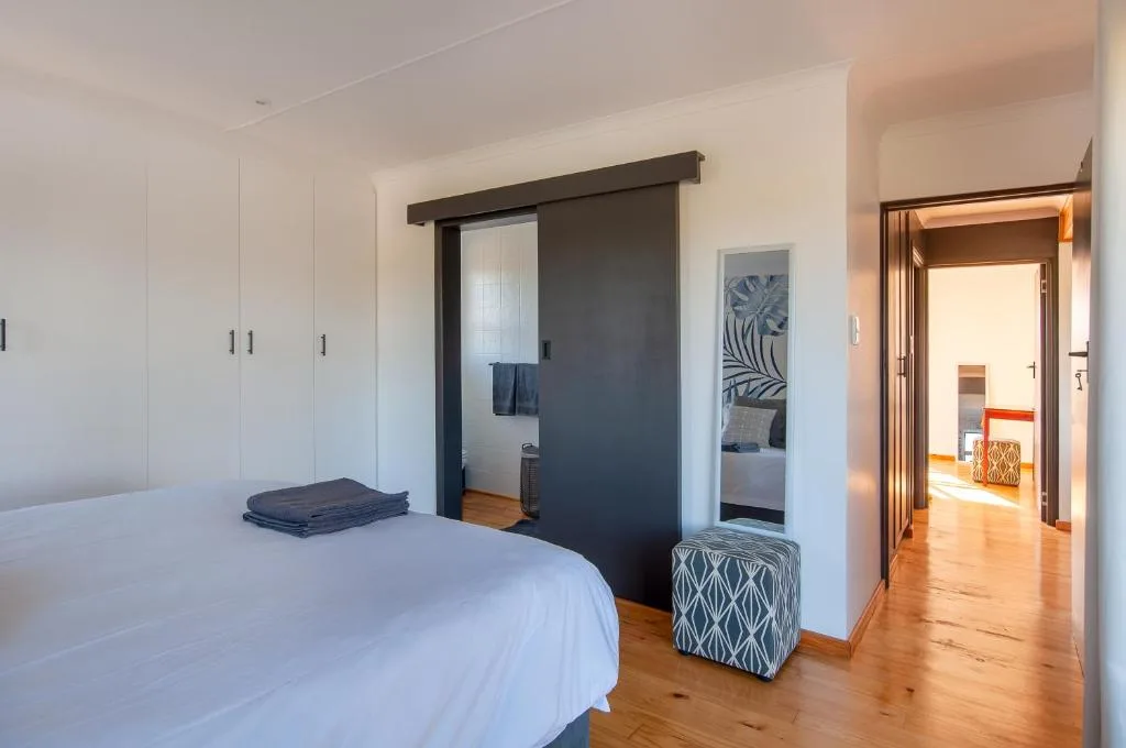 Spacious bedroom with queen bed, built-in wardrobes, and ensuite access
