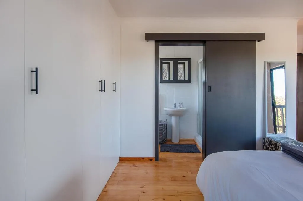 Bright bedroom with wooden floors, white wardrobe, and ensuite bathroom access