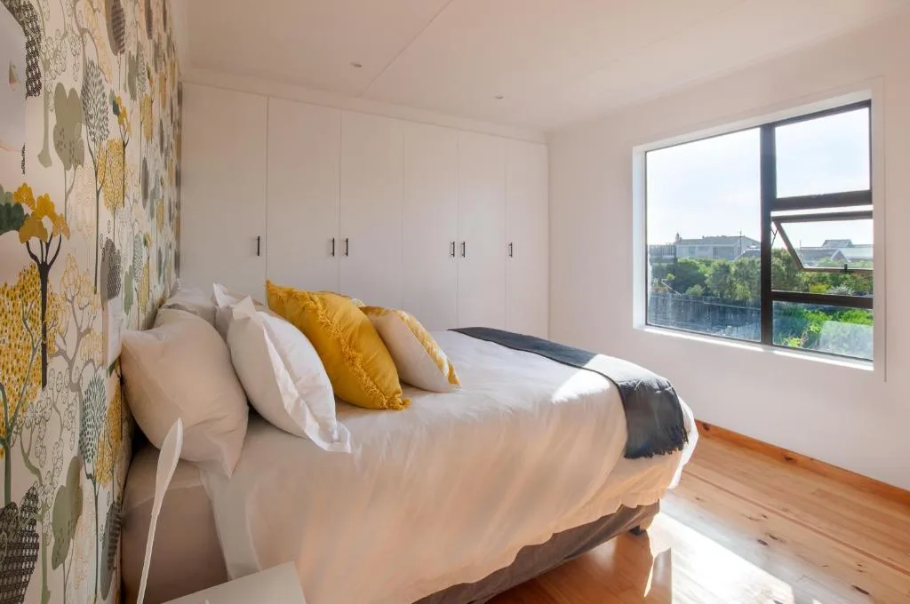 Bright bedroom with queen bed, yellow pillows, botanical wallpaper, built-in wardrobes