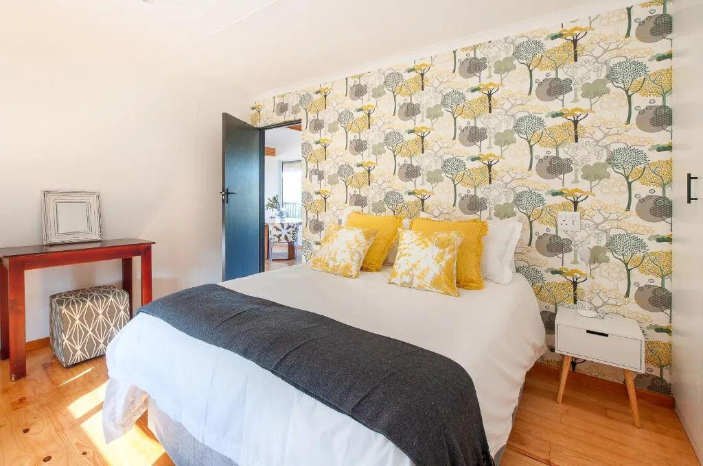 Bright bedroom with queen bed, yellow pillows, tree-patterned wallpaper accent wall