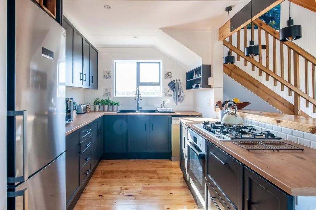 Modern kitchen with dark cabinetry, wooden counters, stainless steel appliances