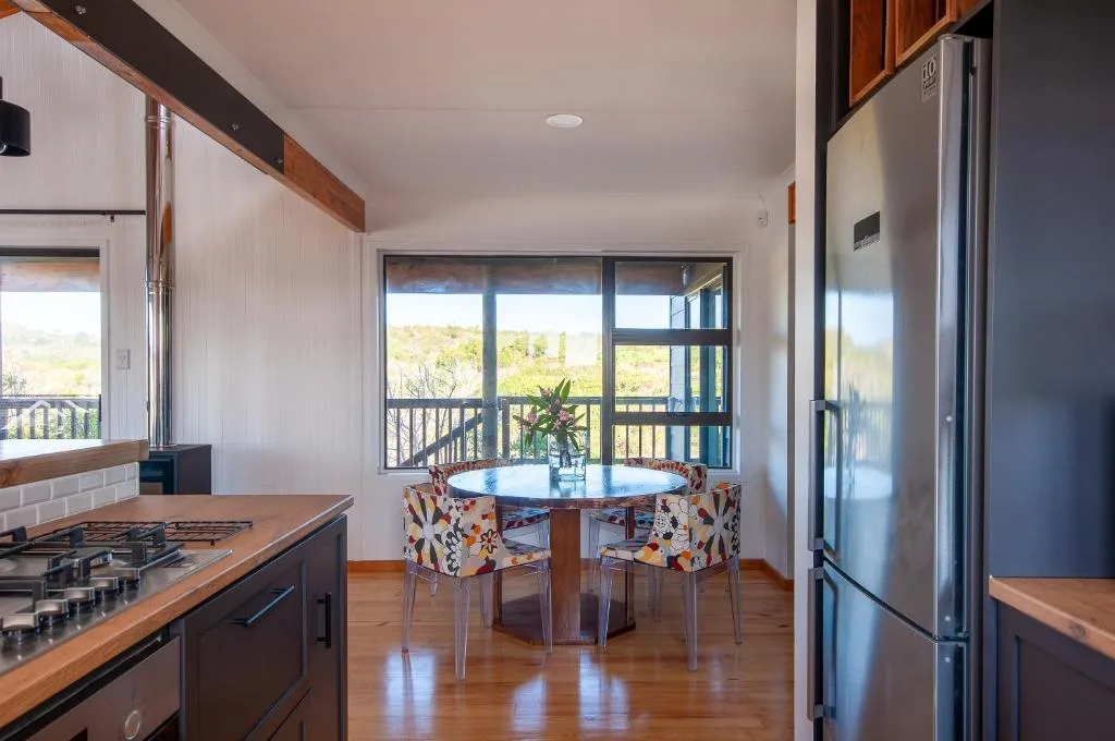 Modern kitchen with gas cooktop, stainless refrigerator, and dining area with scenic views