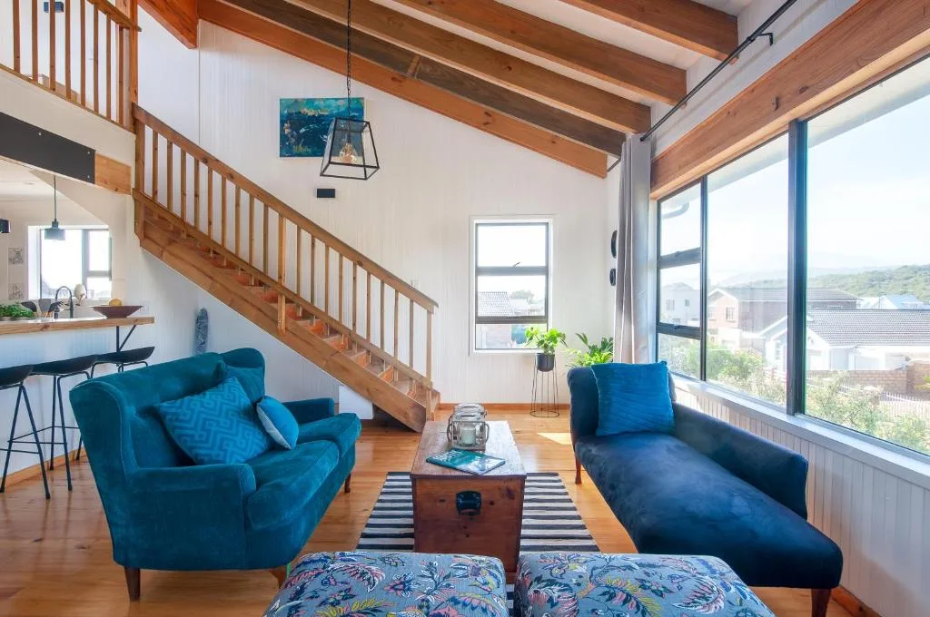 Open-plan lounge with blue velvet seating, wooden beams, and large windows