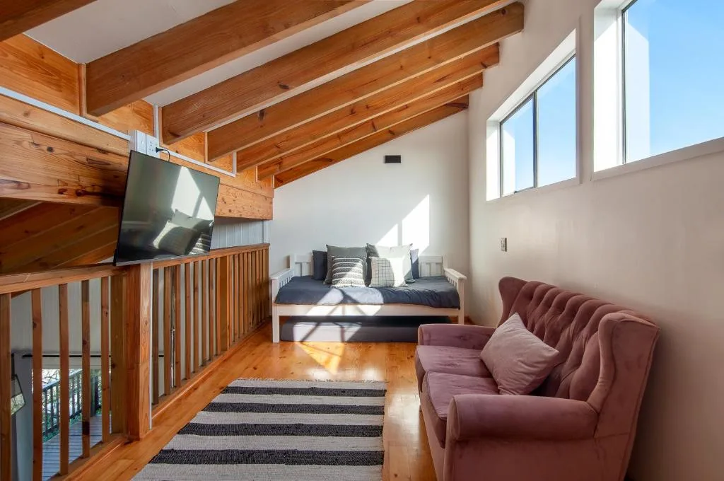 Open-plan lounge with burgundy armchair, TV, and bed visible in background