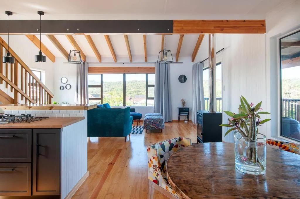 Modern lounge with teal sofa, wooden beams, and garden views