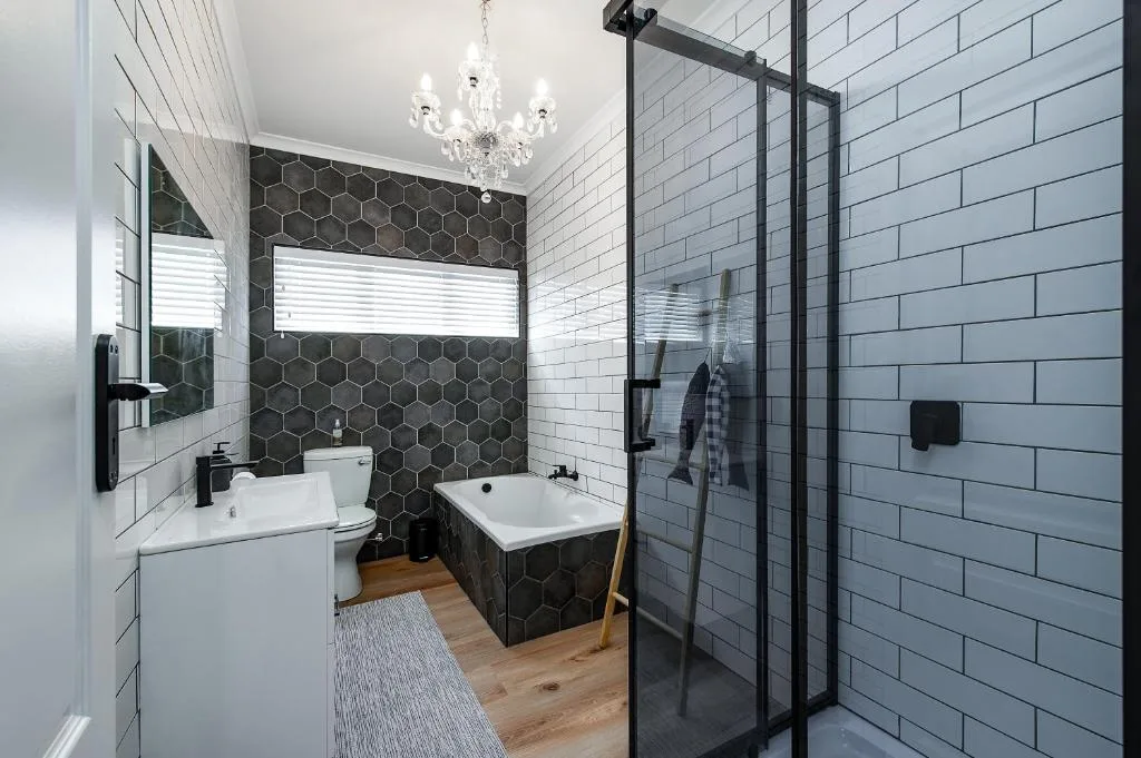 Modern bathroom with hexagonal black tiles, white subway tiles, and freestanding tub