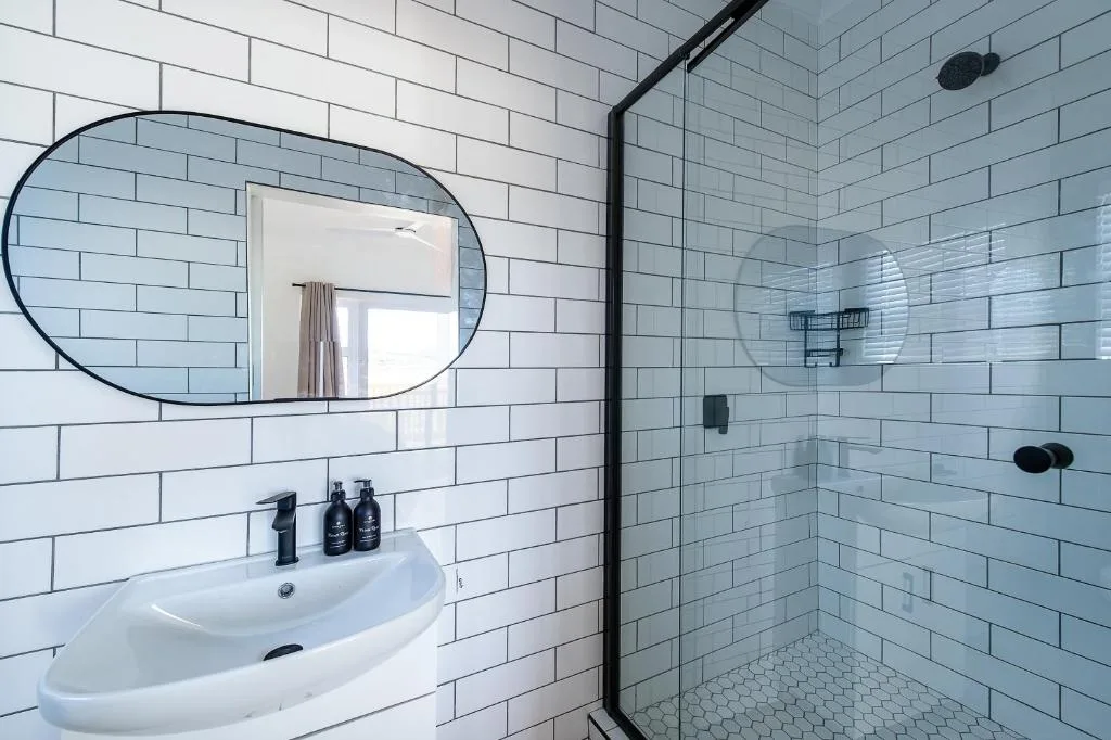 Modern bathroom with white subway tile, rounded mirror, curved vanity sink