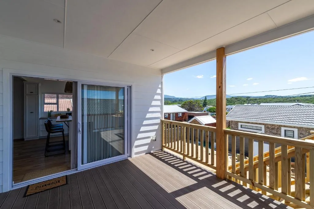 Wooden deck with railing overlooking rural landscape and mountains