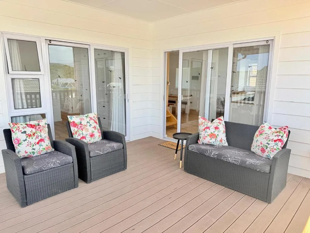 Spacious wraparound deck with rattan seating and floral cushions overlooking hills