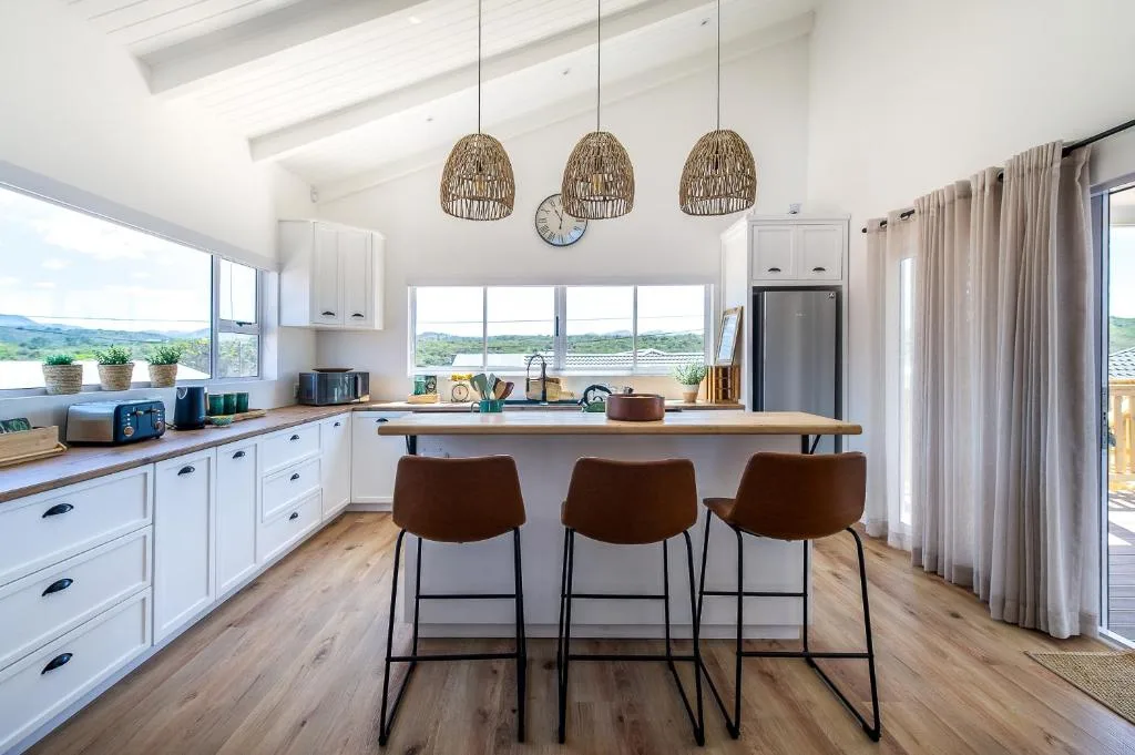 Modern open-plan kitchen with white cabinetry, island seating, and scenic valley views